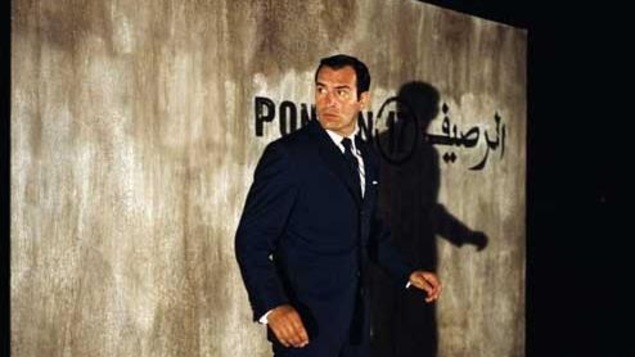 Un homme devant un mur où apparaissent des mots en français et en arabe. Un homme devant un mur où apparaissent des mots en français et en arabe.