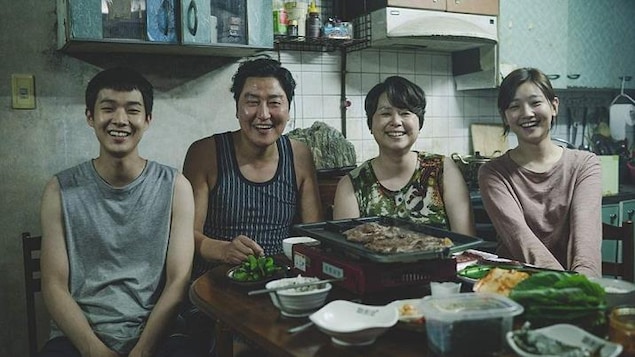 Une famille coréenne de quatre assis à la table de la cuisine, et souriant au photographe.