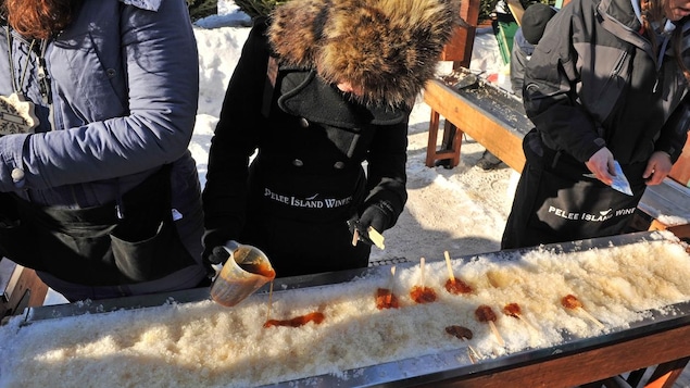 Une femme étend du sirop d'érable sur la neige Une femme étend du sirop d'érable sur la neige