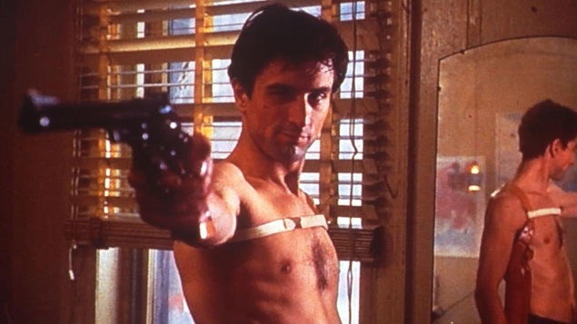 Un homme torse nu, devant un miroir, vise avec un revolver.