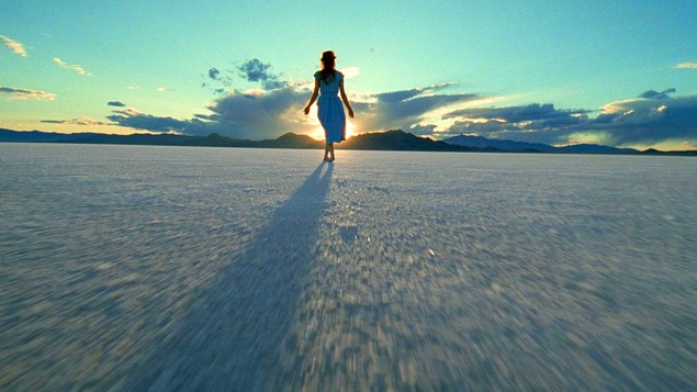 Une femme de dos marche dans un désert. Une femme de dos marche dans un désert.