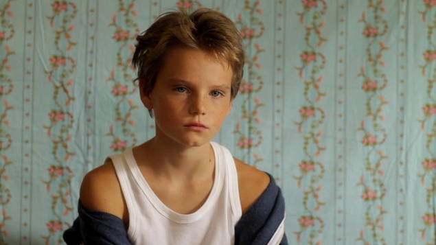 Une petite fille androgyne, en débardeur blanc, regarde devant elle Une petite fille androgyne, en débardeur blanc, regarde devant elle