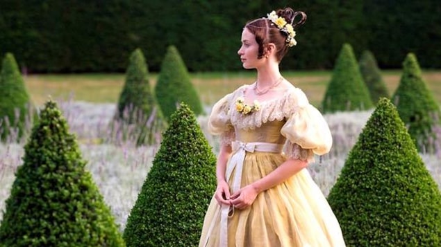 Une femme en robe de bal jaune, dans un jardin taillé. Une femme en robe de bal jaune, dans un jardin taillé.