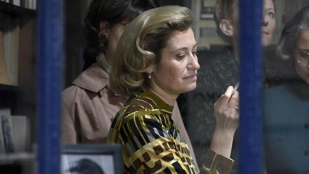 Une femme, dans une librairie, entourée de gens attentifs, fume une cigarette. Une femme, dans une librairie, entourée de gens attentifs, fume une cigarette.