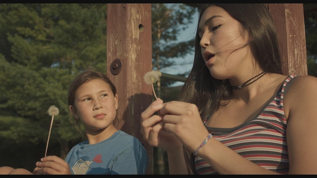 Deux jeunes filles soufflent sur des pissenlits. Deux jeunes filles soufflent sur des pissenlits.