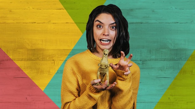 Femme de 30 ans rieuse qui porte une poupée dinosaure