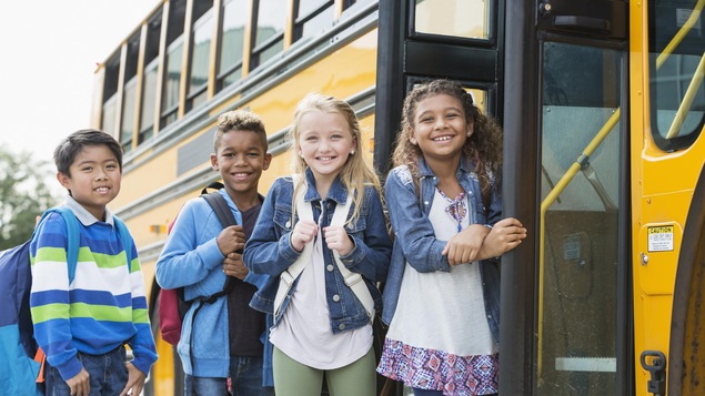 Ils sourient devant le bus scolaire