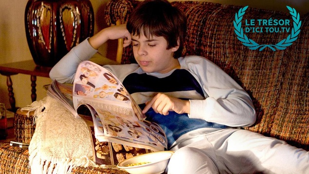 Un garçon en pyjama, sur un sofa, lit un catalogue. Un garçon en pyjama, sur un sofa, lit un catalogue.