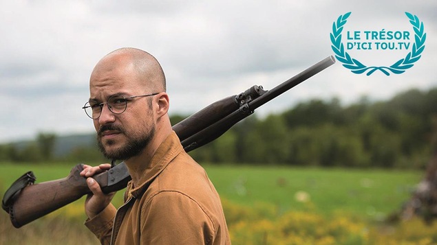 Dans un champ, Marc-André Grondin tient un fusil sur l'épaule dans une scène du film Dans un champ, Marc-André Grondin tient un fusil sur l'épaule dans une scène du film