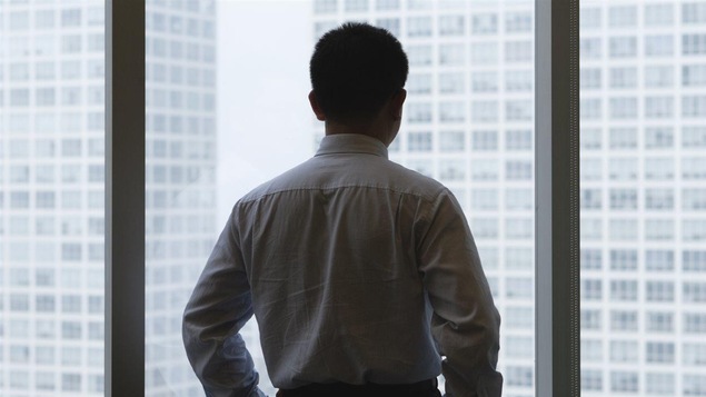 Un homme d'affaires regarde par la fenêtre de son bureau.