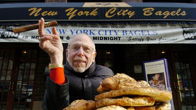 Un homme pose fièrement devant le commerce New York City Bagels