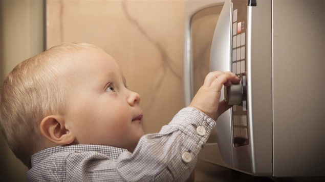 Un bébé devant un four micro-ondes