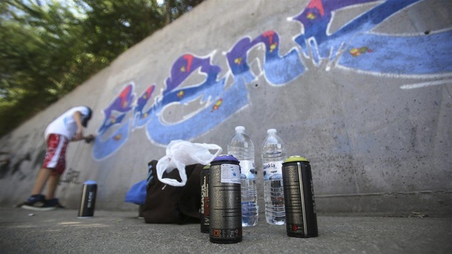 Un jeune peint un graffiti.