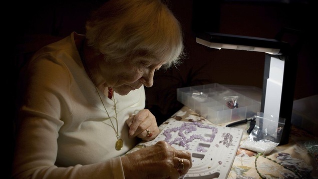 Une femme âgée fait un travail de bijouterie.