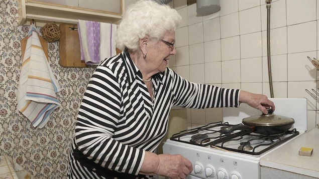 Une femme âgée fait la cuisine.