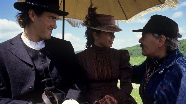 Assis sous une ombrelle, Ovila Pronovost (Roy Dupuis) et Émilie Bordeleau (Marina Orsini) discutant avec le réalisateur Jean Beaudin.