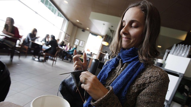 Une jeune femme tricote.