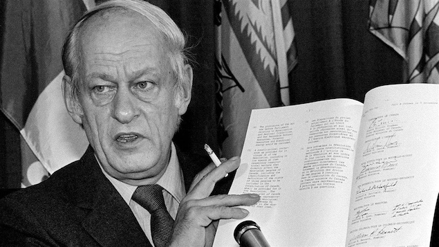 René Lévesque tient l'accord constitutionnel signé par Pierre Elliott Trudeau.
