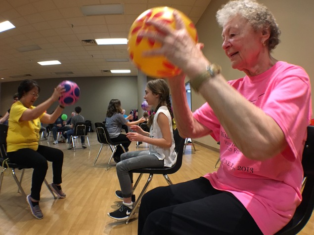 Une aînée participe à un jeu de ballon en compagnie de jeunes d'une école primaire. Une aînée participe à un jeu de ballon en compagnie de jeunes d'une école primaire.