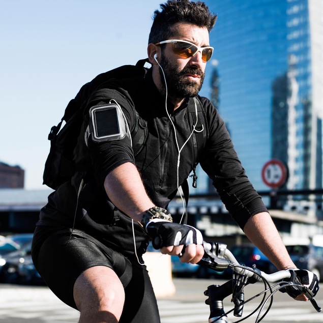 Un cycliste circule alors qu'il porte des écouteurs. Il porte aussi des verres fumés et semble se trouver en milieu urbain. Un cycliste circule alors qu'il porte des écouteurs. Il porte aussi des verres fumés et semble se trouver en milieu urbain.