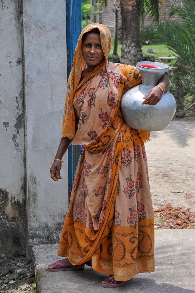Une femme marche avec une cruche d’eau.