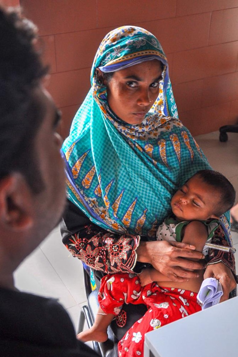Un jeune enfant dort dans les bras de sa mère lors d’une consultation médicale.