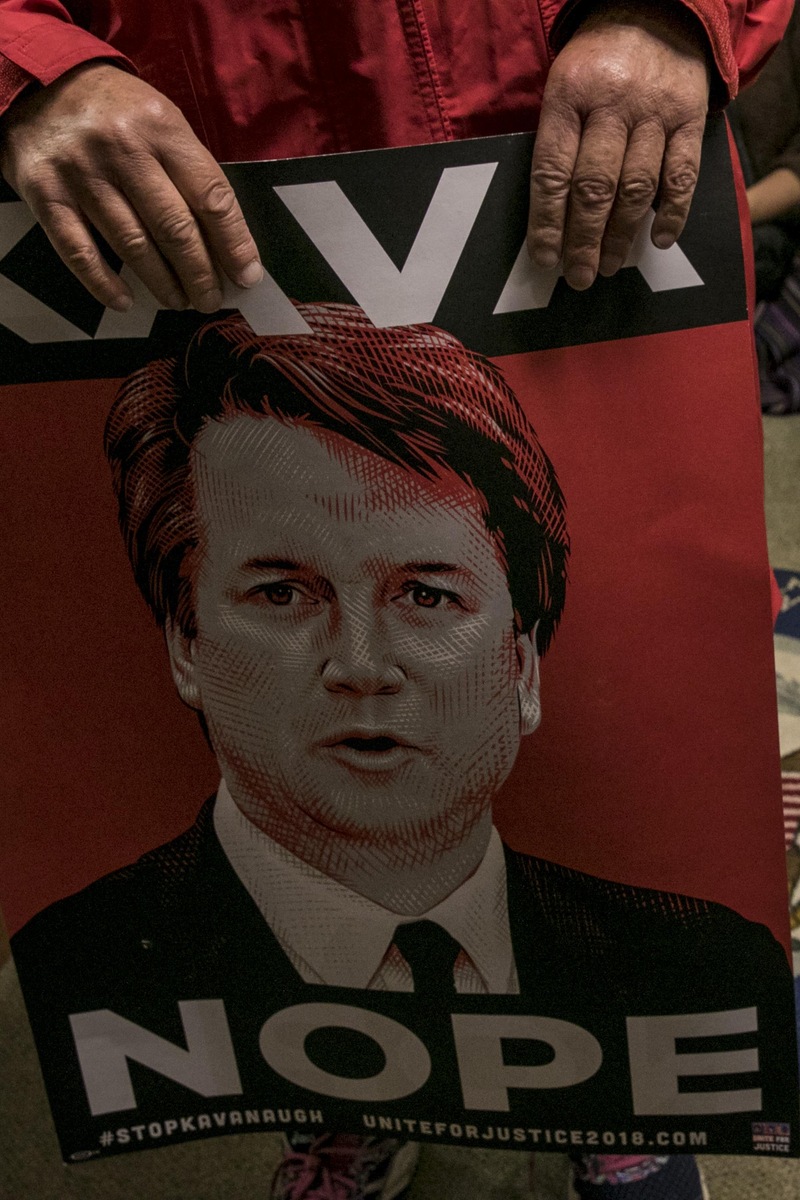 Des femmes participent à un sit-in dans le bureau de la sénatrice Susan Collins, à Portland, dans le Maine, le 28 septembre 2018, pour l'exhorter à voter contre la confirmation de Brett Kavanaugh. Elles tiennent une affiche sur laquelle est écrit : «Pas de Kavanaugh».