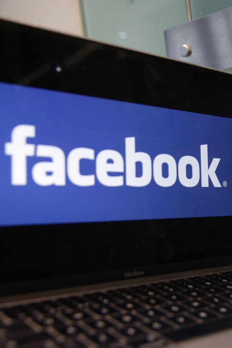 Un ordinateur portable affichant le logo de Facebook est posé à côté d'un panneau de Cambridge Analytica indiquant l'entrée des bureaux de l'entreprise à Londres, le 21 mars 2018.
