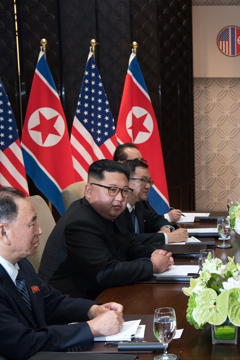 Donald Trump et Kim Jong-un sont assis face à face entourés de leurs délégation lors du sommet entre les États-Unis et la Corée du Nord à l'hôtel Capella, à l'île Sentosa, à Singapour, le 12 juin 2018.