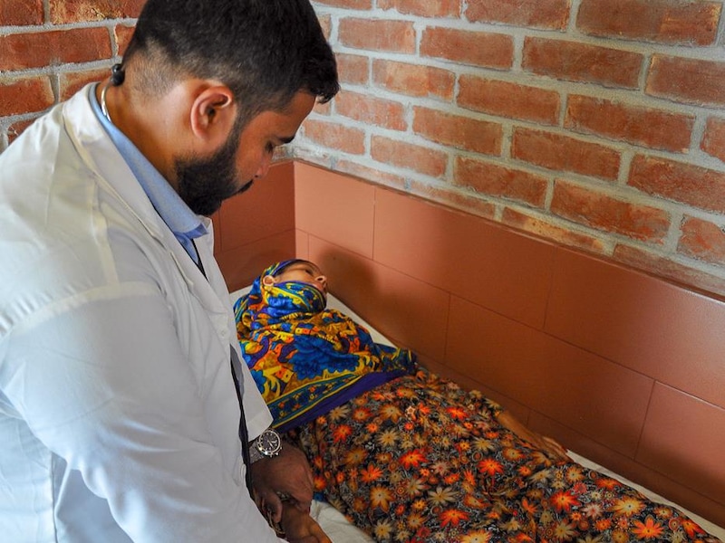 Dans un hôpital, un docteur examine une patiente couchée sur une civière.