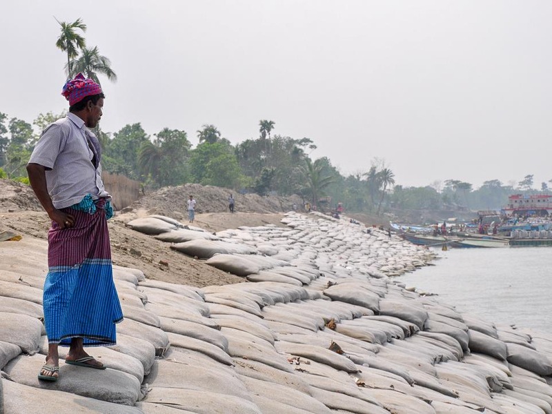 Un homme observe les berges recouvertes de sacs de sable.