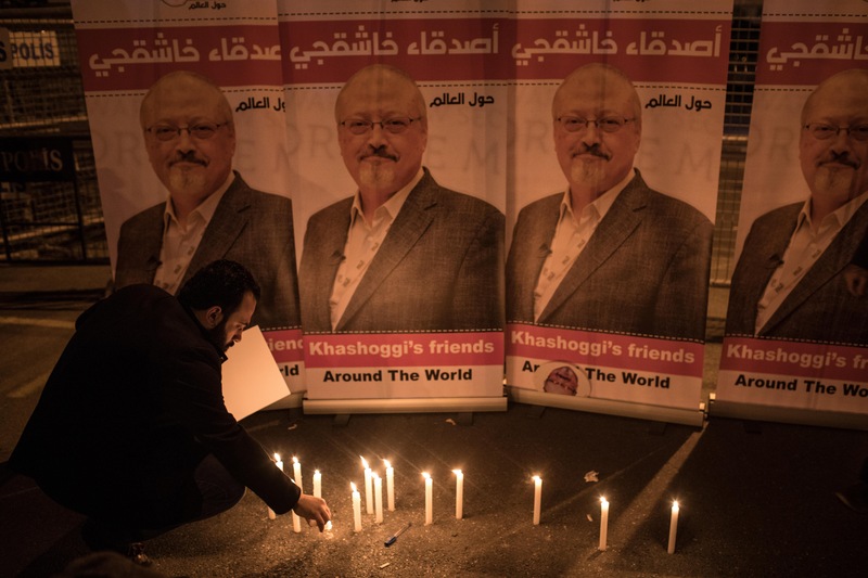 Un homme allume une chandelle devant des affiches de Jamal Khashoggi pendant une vigile en souvenir du journaliste devant le consulat de l'Arabie saoudite à Istanbul, le 25 octobre 2018.