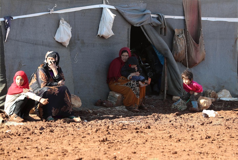 Des femmes et des enfants syriens déplacés sont assis devant leur tente dans le camp de Kafr Dariyan, à proximité de la frontière avec la Turquie, le 26 octobre 2018.