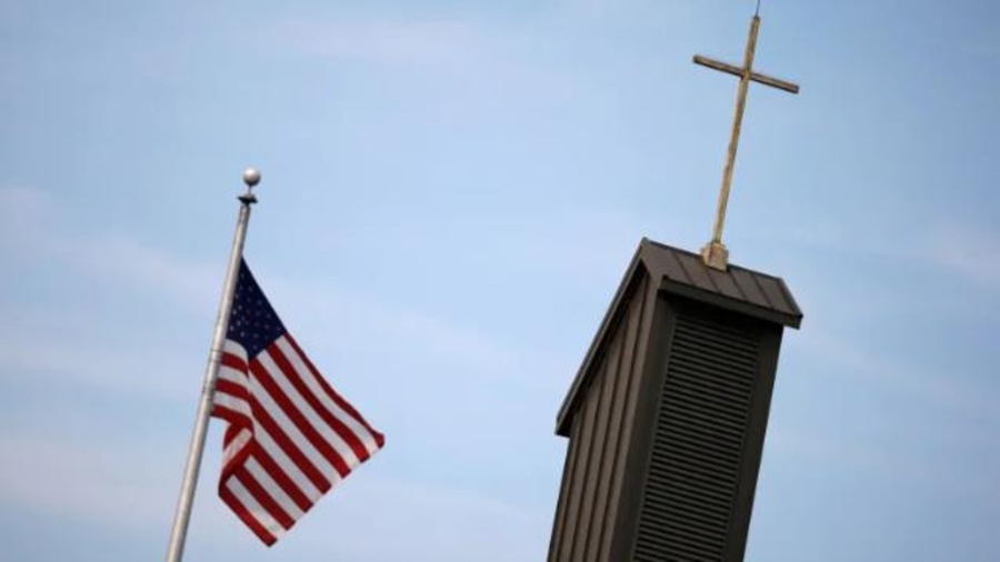 Le drapeau des États-Unis flotte dans les airs à côté du clocher d'une église catholique. Le drapeau des États-Unis flotte dans les airs à côté du clocher d'une église catholique.