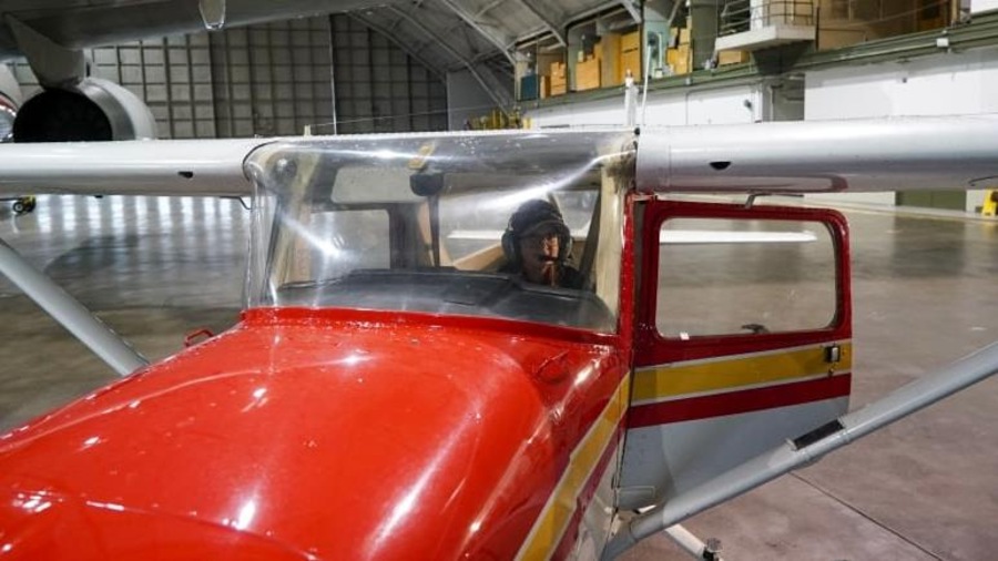 Sara Striker vue à travers le pare-brise d'un petit avion dans un hangar. Sara Striker vue à travers le pare-brise d'un petit avion dans un hangar.