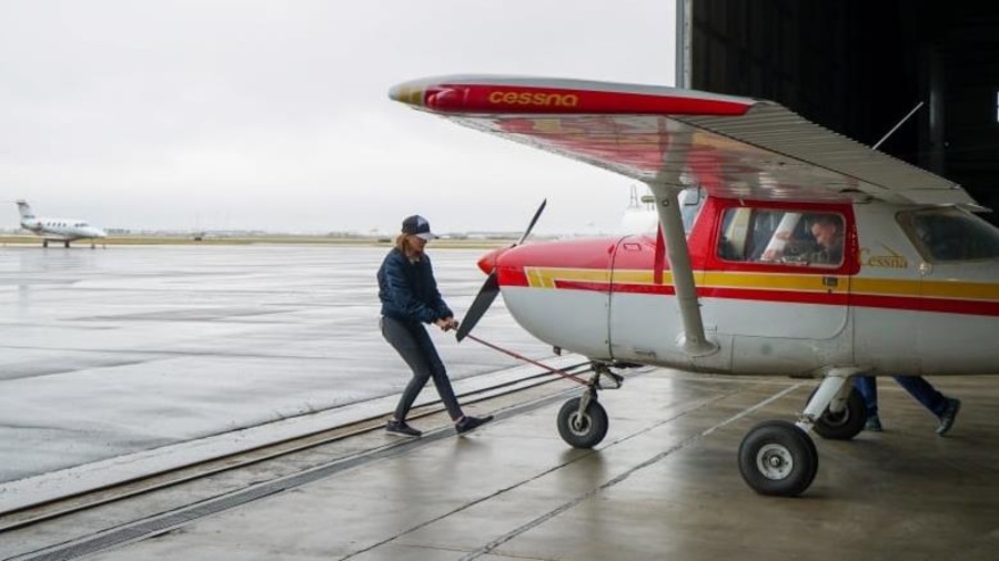 Sara et son père poussent un petit avion hors du hangar. Sara et son père poussent un petit avion hors du hangar.