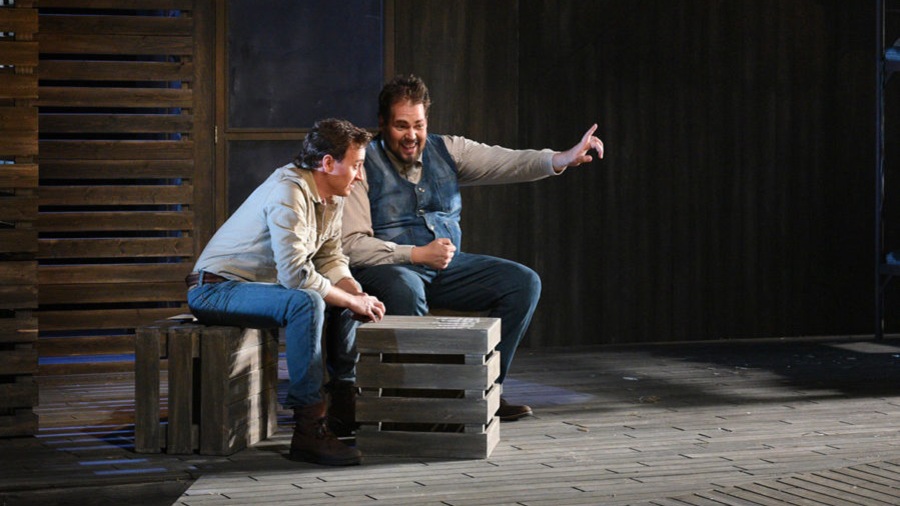 George (Benoît McGinnis) et Lennie (Guillaume Cyr) sont en pleine discussion, assis sur des caisses de bois, au coeur d'un décor de lattes de bois en clair-obscur. George (Benoît McGinnis) et Lennie (Guillaume Cyr) sont en pleine discussion, assis sur des caisses de bois, au coeur d'un décor de lattes de bois en clair-obscur.