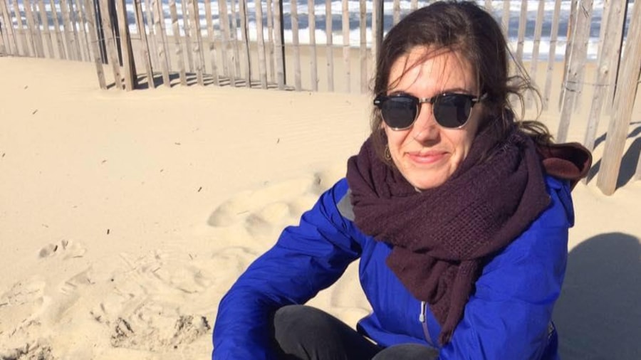 Elle est assise sur une plage, foulard au cou et manteau bleu. Elle est assise sur une plage, foulard au cou et manteau bleu.