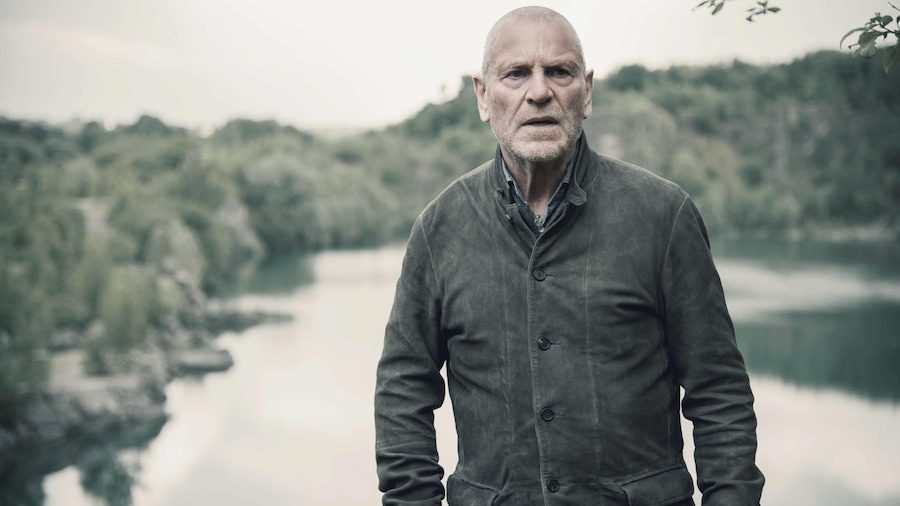 Un homme se tient debout devant un lac.