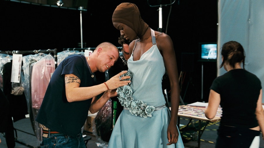 Un homme tatoué et en t-shirt arrange une robe sur un mannequin. Un homme tatoué et en t-shirt arrange une robe sur un mannequin.
