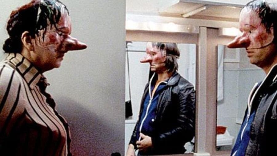 Une femme (Yolande Moreau) et un homme portant des masques se font face. Une femme (Yolande Moreau) et un homme portant des masques se font face.