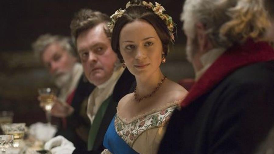 Une femme en robe de bal, une couronne de fleurs sur la tête, assise à table, au milieu d'hommes. Une femme en robe de bal, une couronne de fleurs sur la tête, assise à table, au milieu d'hommes.