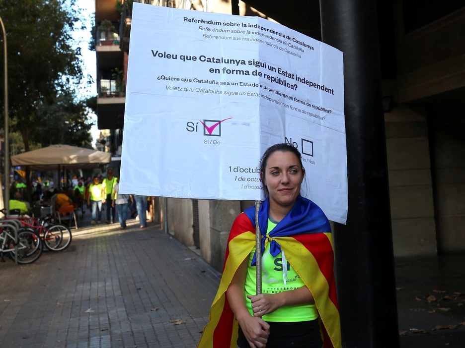 Une manifestante tient une pancarte illustrant un bulletin de vote où le "oui" est coché. Une manifestante tient une pancarte illustrant un bulletin de vote où le "oui" est coché.