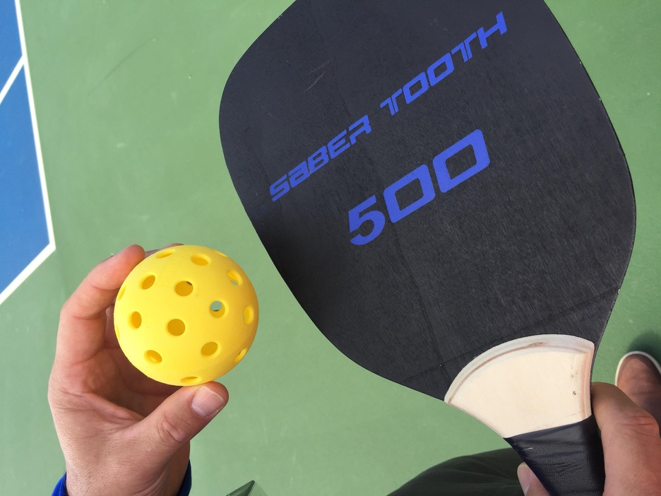 Une balle et une raquette de pickleball. Une balle et une raquette de pickleball.