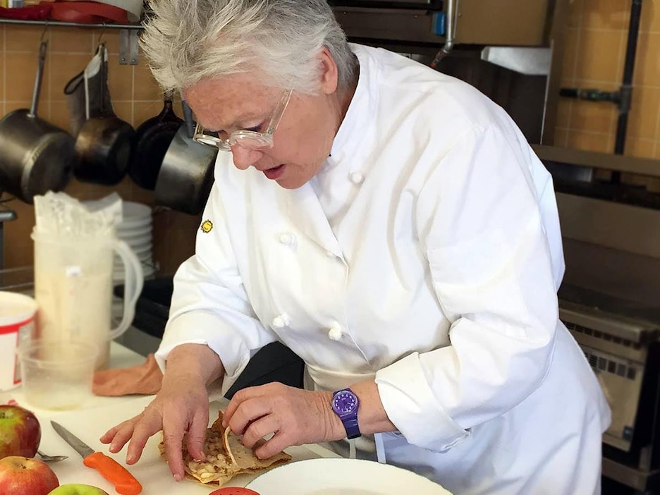 Une femme en uniforme blanc de restaurant prépare un plat. Une femme en uniforme blanc de restaurant prépare un plat.