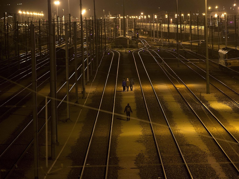Quatre personnes marchent le soir près de rails de train. Quatre personnes marchent le soir près de rails de train.