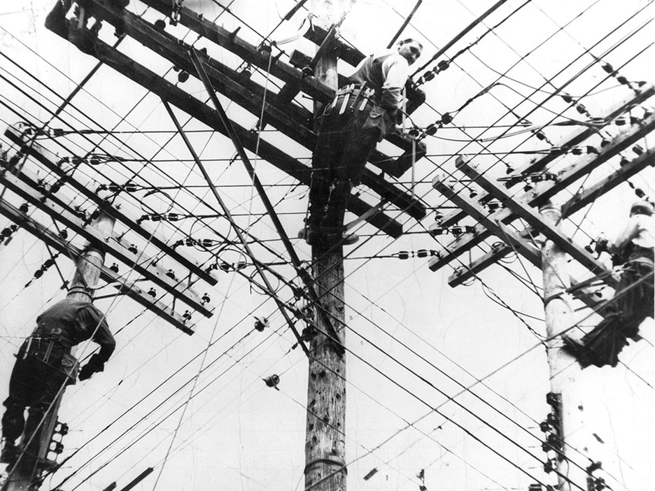 Photo en contre-plongée d'ouvriers juchés dans des poteaux d'électricité Photo en contre-plongée d'ouvriers juchés dans des poteaux d'électricité
