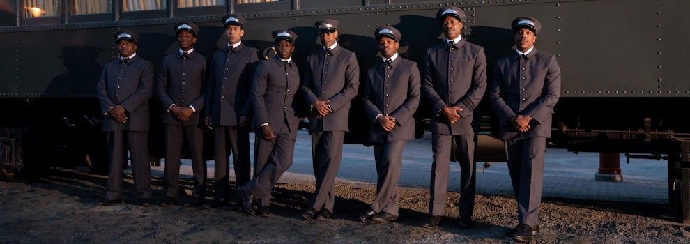 Des porteurs en uniformes sont alignés devant un wagon de train.